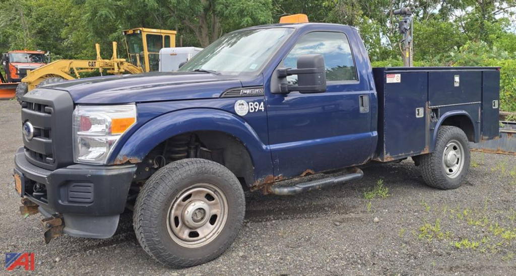 Ford F-350 Super Duty with utility utility box and plow, blue cab over 4x4 work truck, front left view showing side toolbox and plow mount.