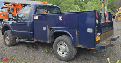 Ford F-350 Super Duty utility service truck with plow and utility box, blue cab and cargo bed, side view showing storage compartments and rear bumper, used condition.