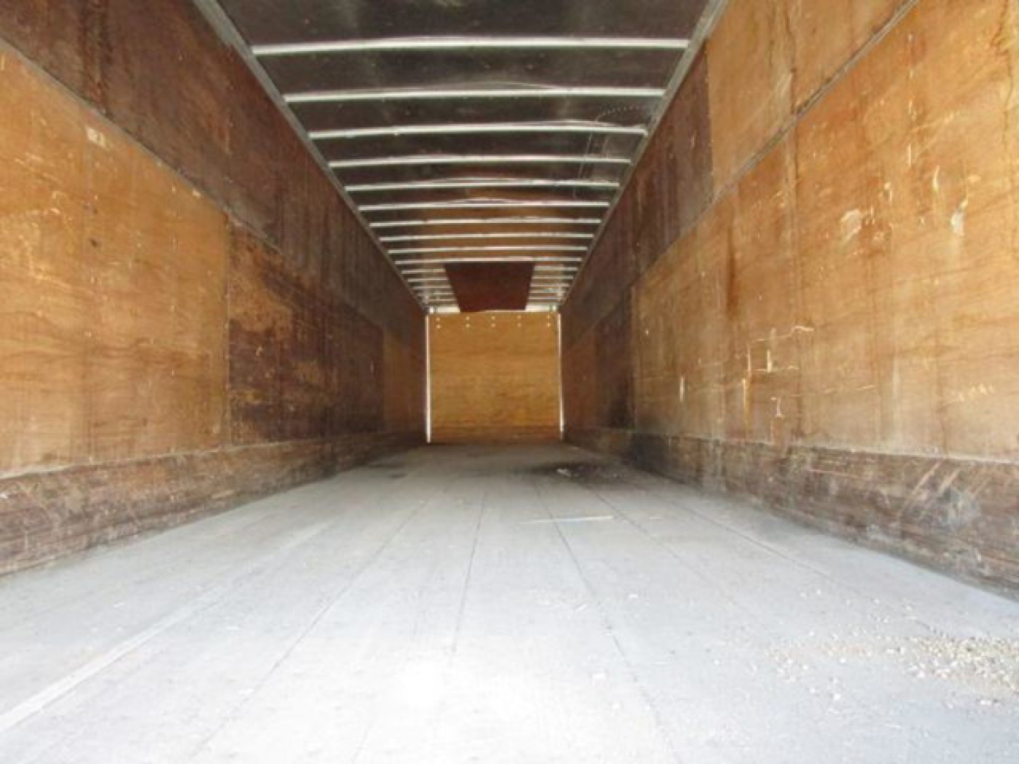 Trailer interior showing empty cargo bay with wooden side walls and metal roof beams.