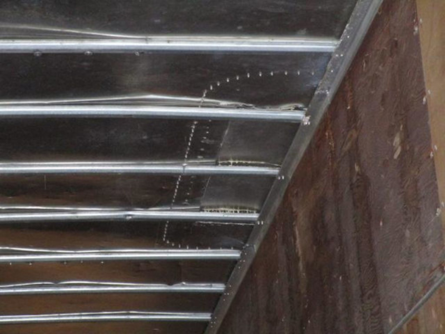 Trailer side interior with metal rails and rusted wall, no readable text.