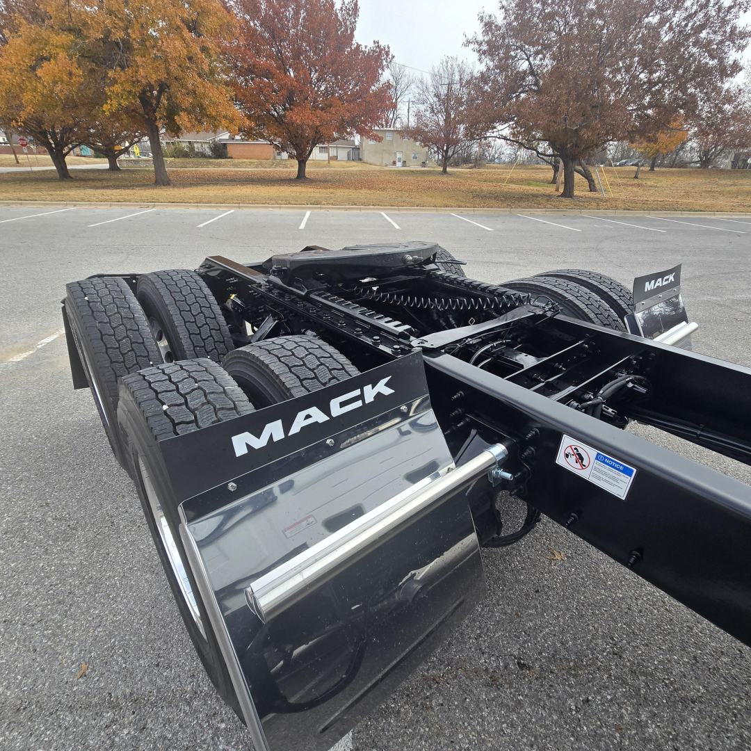 Mack PR64T76M frame and rear axle assembly showing tandem drive tires and chassis with Mack branding on the mud flaps and fuel/air lines.