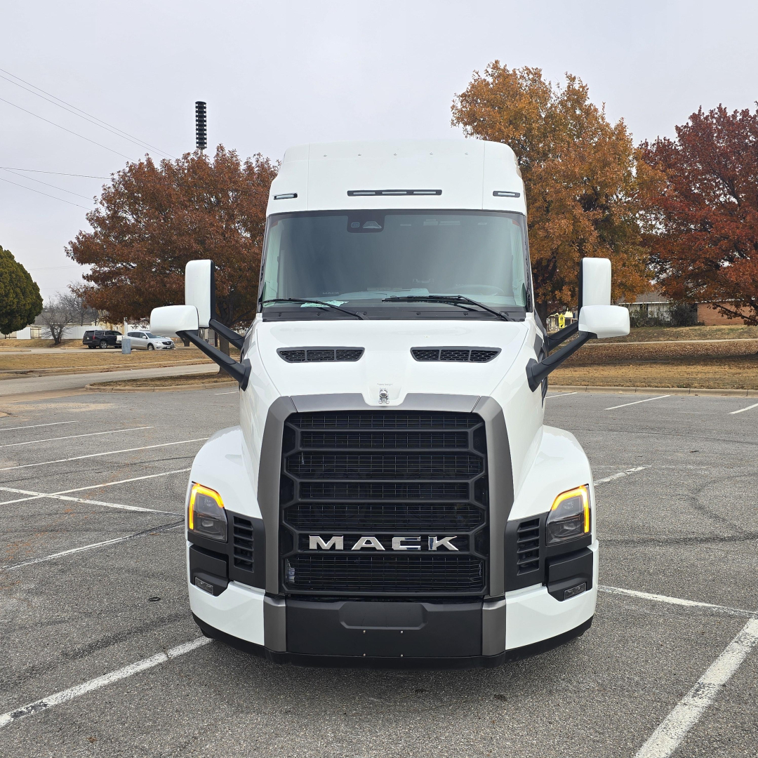 White Mack PR64T76M truck front view with large grille, black bumper, and LED daytime running lights. Mack logo on grille.