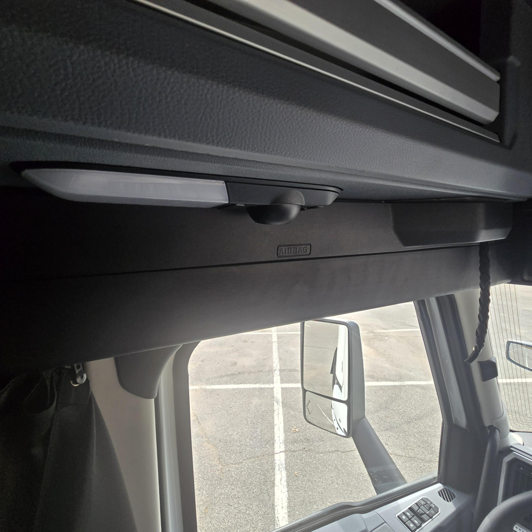 Cab interior showing ceiling-mounted rearview mirror and overhead storage on Mack PR64T76M truck cabin.