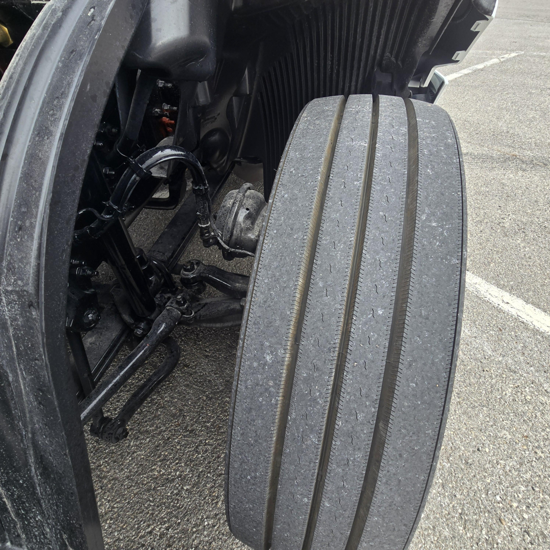 Mack PR64T76M truck front brake pedal and step showing textured running board and part of front suspension and wheel well.
