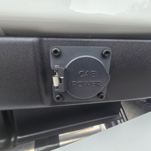 Round power inlet cover labeled 'GAB POWER' on a truck bumper, with a spring latch and four screws.