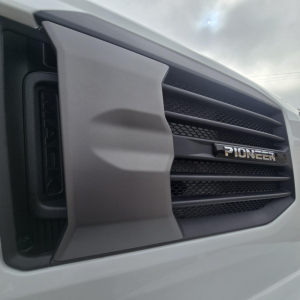 Front grille of a Mack truck showing the Pioneer badge and horizontal slats in a light-colored bumper area.