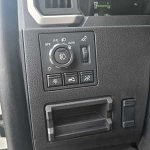 Dashboard controls panel of a Mack PR64T76M truck showing headlight dial, fog light symbol, and auxiliary buttons.