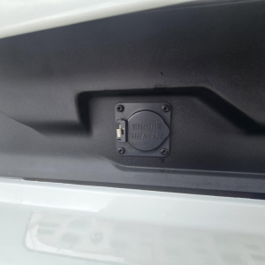 Engine heater  plug cover on Mack PR64T76M truck engine bay showing circular cap labeled ENGINE HEATER