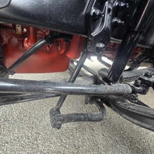 Front axle and undercarriage view of a new Mack PR64T76M truck showing suspension linkage and frame components.