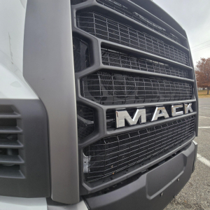 Mack PR64T76M truck grille close-up showing MAC K logo and front fascia; front bumper and mesh grille visible.