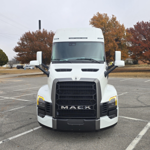 White Mack PR64T76M truck front view with large grille, black bumper, and LED daytime running lights. Mack logo on grille.