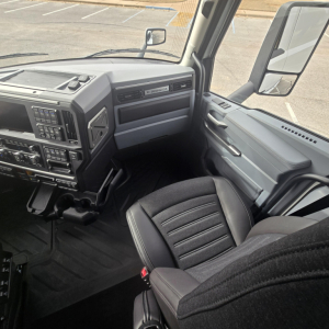 Cab interior of a 2026 Mack PR64T76M truck showing dashboard, steering column, and front passenger seat with grey and black trim.