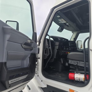 Mack PR64T76M truck interior and cabin door open showing steering wheel and dashboard.