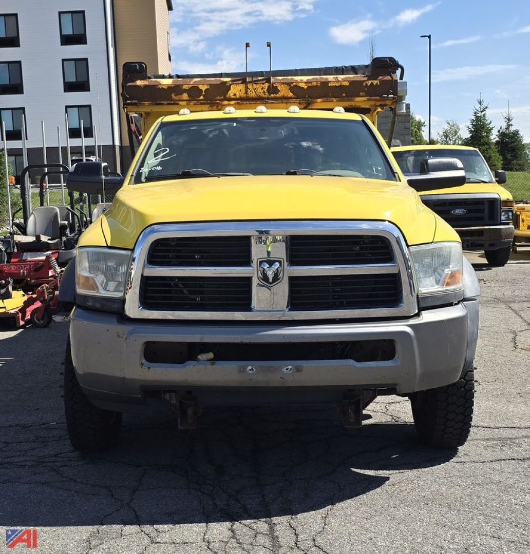 Yellow 2011 Dodge Ram 5500 cab chassis with front grille, plow truck, and rusted dump bed mounted on top, front view.