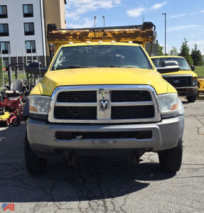Yellow 2011 Dodge Ram 5500 cab chassis with front grille, plow truck, and rusted dump bed mounted on top, front view.