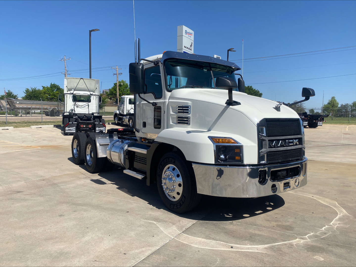 Prime white 2021 Mack AN64T conventional daycab truck side-front view showing dual rear axles, large grille, chrome bumper, and Mack badge.
