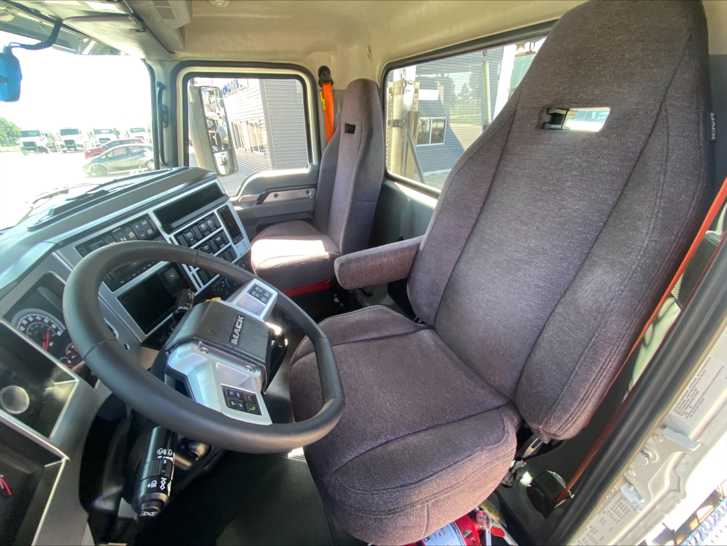 Cab interior of a 2021 Mack AN64T showing steering wheel, driver's seat, and dashboard with gauges and controls.