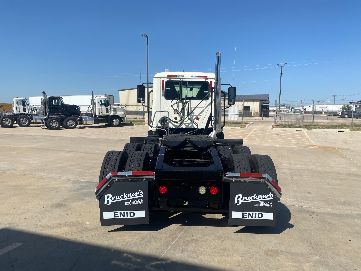 Rear view of a white 2021 Mack AN64T daycab tractor showing dual rear mudflaps with Bruckner's Equipment logos and ENID text.