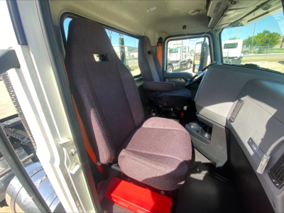 Cab interior of a Mack AN64T conventional daycab showing steering wheel, driver seat, passenger seat, and dashboard in view.