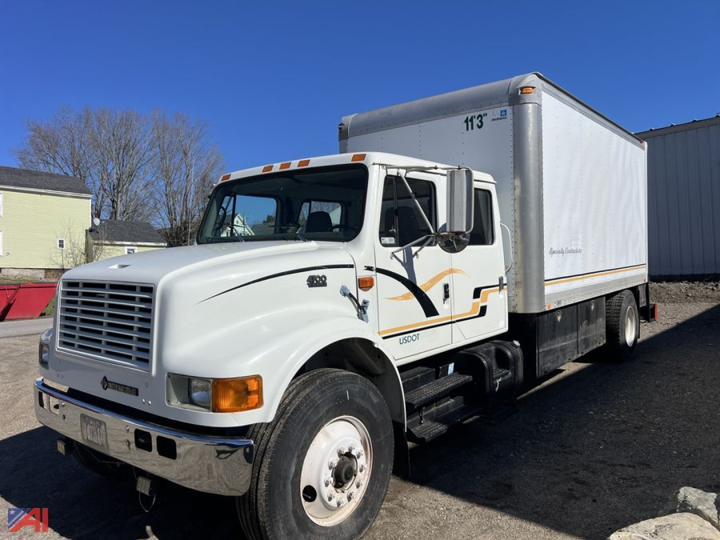 International 4700 crew cab box truck with 16 ft box, white cab and trailer, side graphic stripe, front grille view, daytime outdoor lot