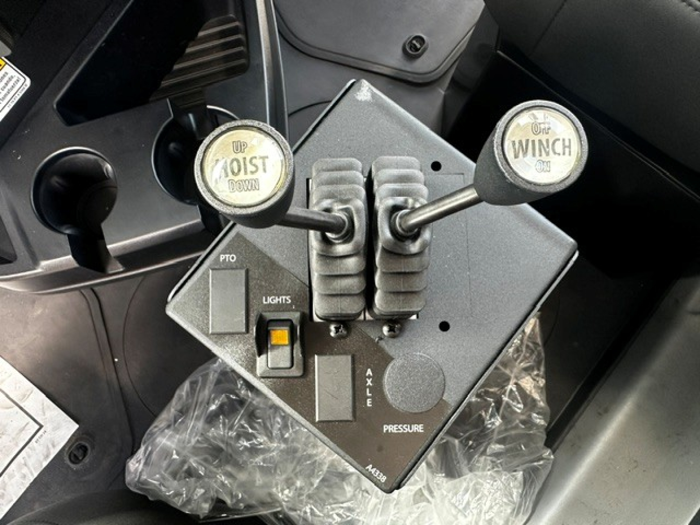 Mack GR64B control pedestal with levers labeled UP/DOWN and WINCH, showing PTO, LIGHTS switch, and AXLE/PRESSURE indicators.