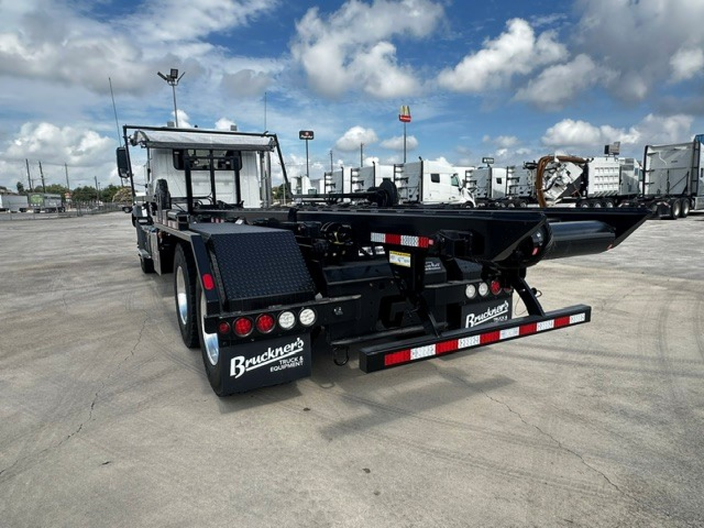 Back of 2026 Mack GR64B roll-off truck showing rear bumper and taillights.