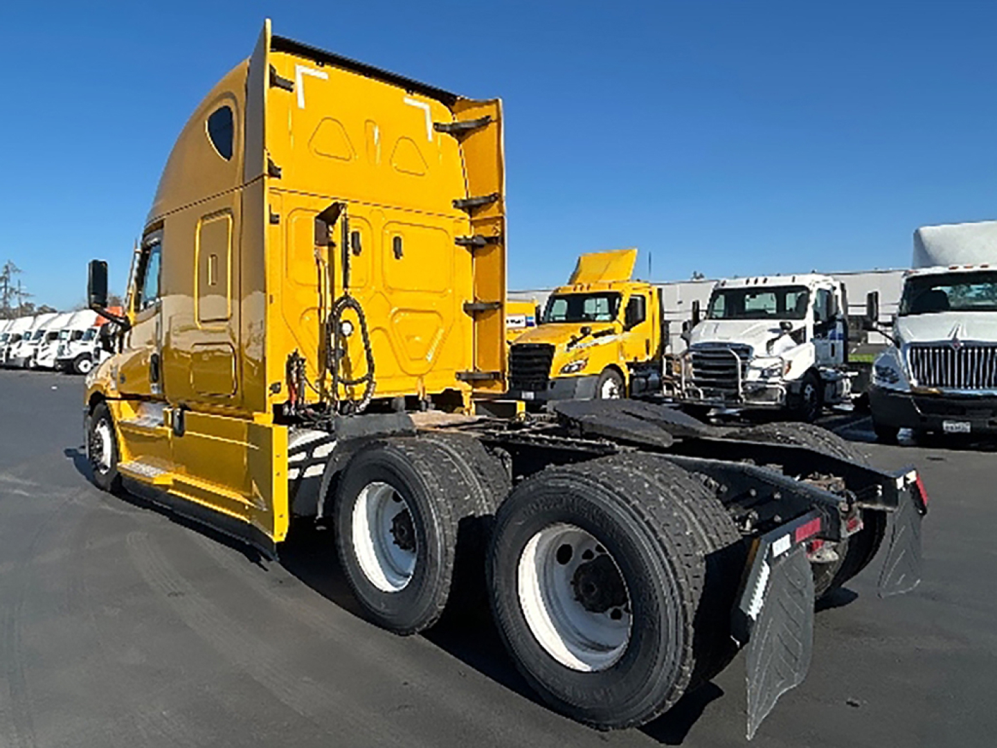 Rear and side view of a yellow Freightliner Cascadia126 semi-truck tractor showing the chassis and rear wheels.