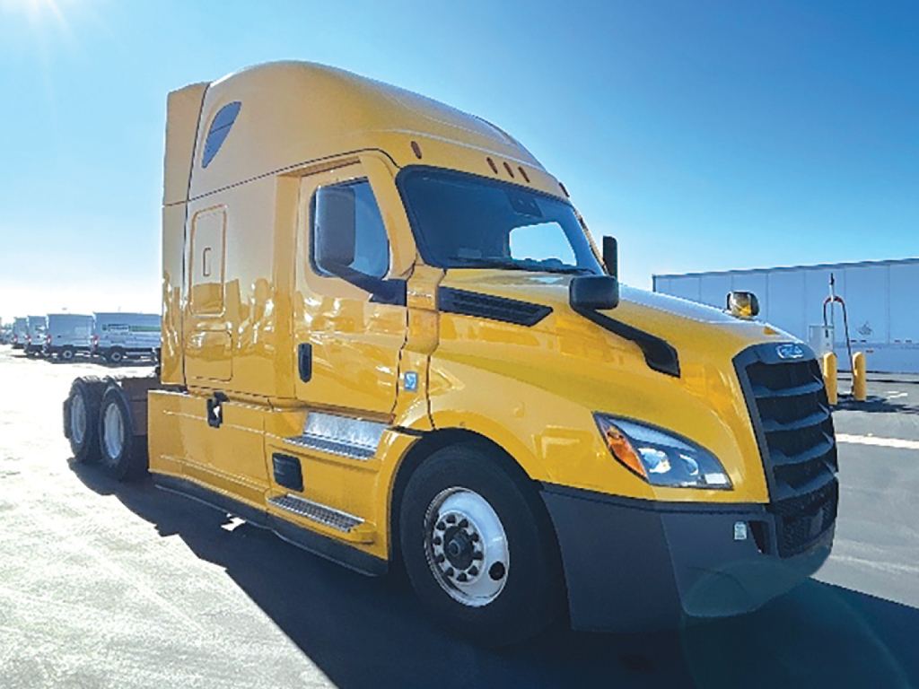 Truck cab with bright yellow Freightliner Cascadia126 in a parking lot. No visible text on the vehicle exterior.