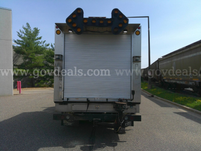 Rear view of 2018 Freightliner M2-106 service/utility truck with roll-up cargo door and arrow lights.