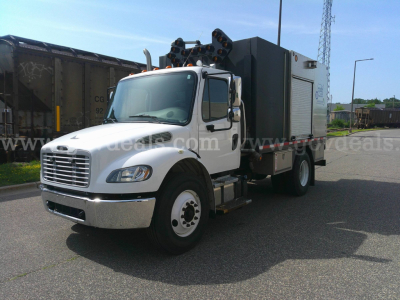 Truck engine bay area showing Freightliner M2-106 utility service body with mounted equipment and cab side view.