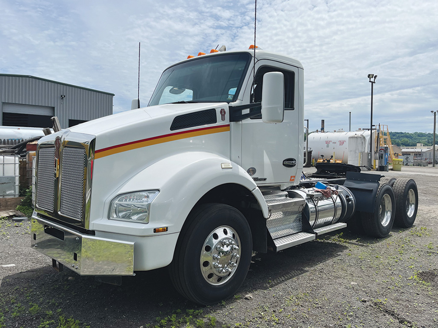 Kenworth T-880 conventional daycab truck in white with chrome bumper, grille, and dual rear axles. Side shows fuel tanks and steps; headlights and amber clearance lights visible.