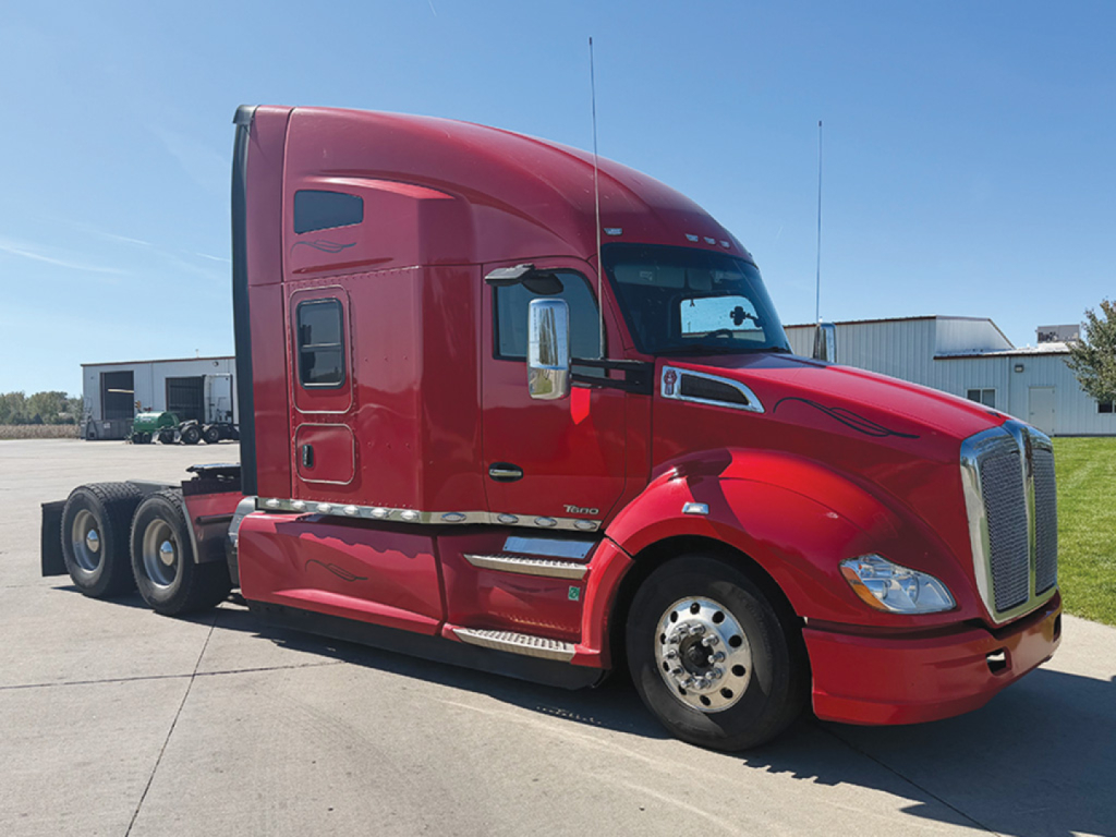 Kenworth T-680 tractor cab in red, side view showing sleeper with aerodynamic hood and dual rear bogies.