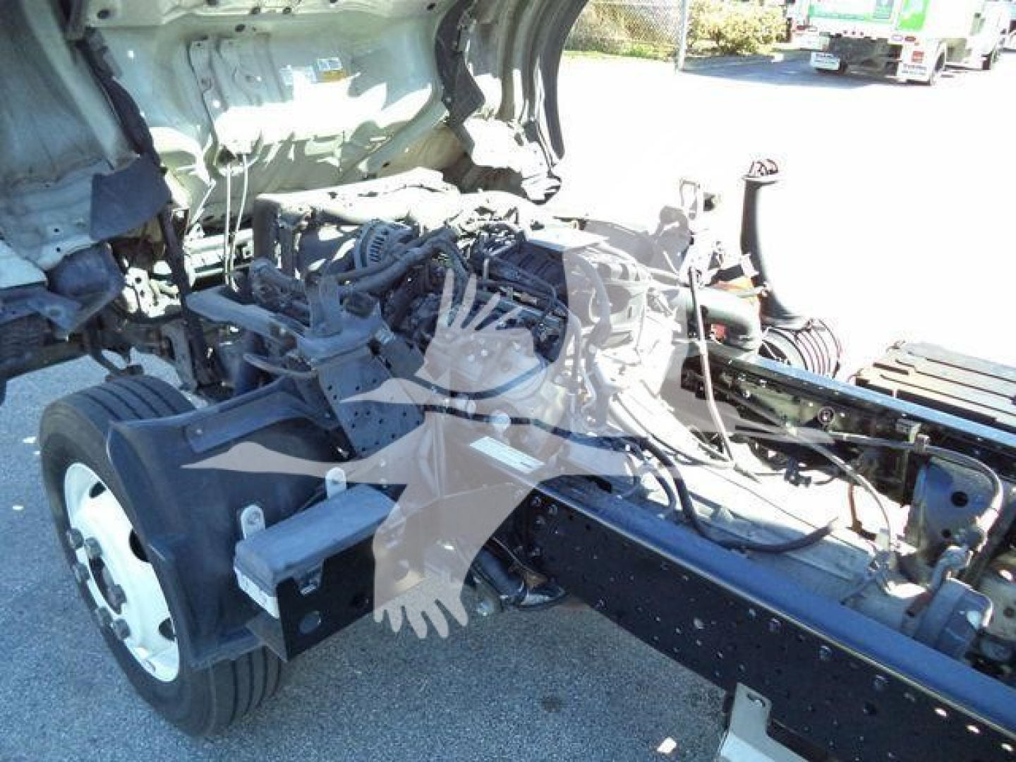 Isuzu NPR-HD chassis and engine bay exposed, cab removed showing front axle, suspension, and engine mounting area with visible wiring and components.