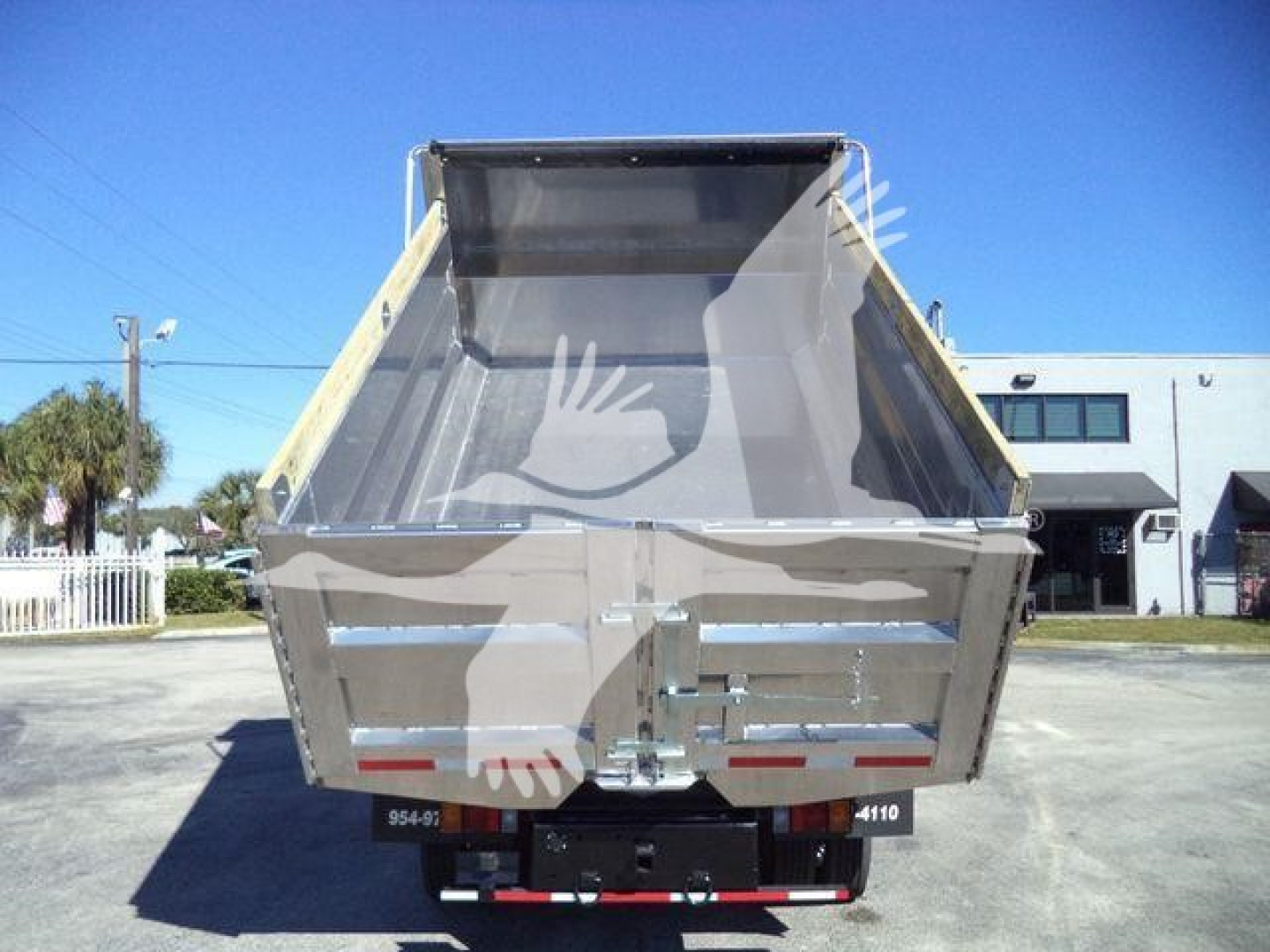 Isuzu NPR-HD dump truck rear view showing cargo bed and tailgate with reflective tape. Visible text on license area: 954-93, 4110.