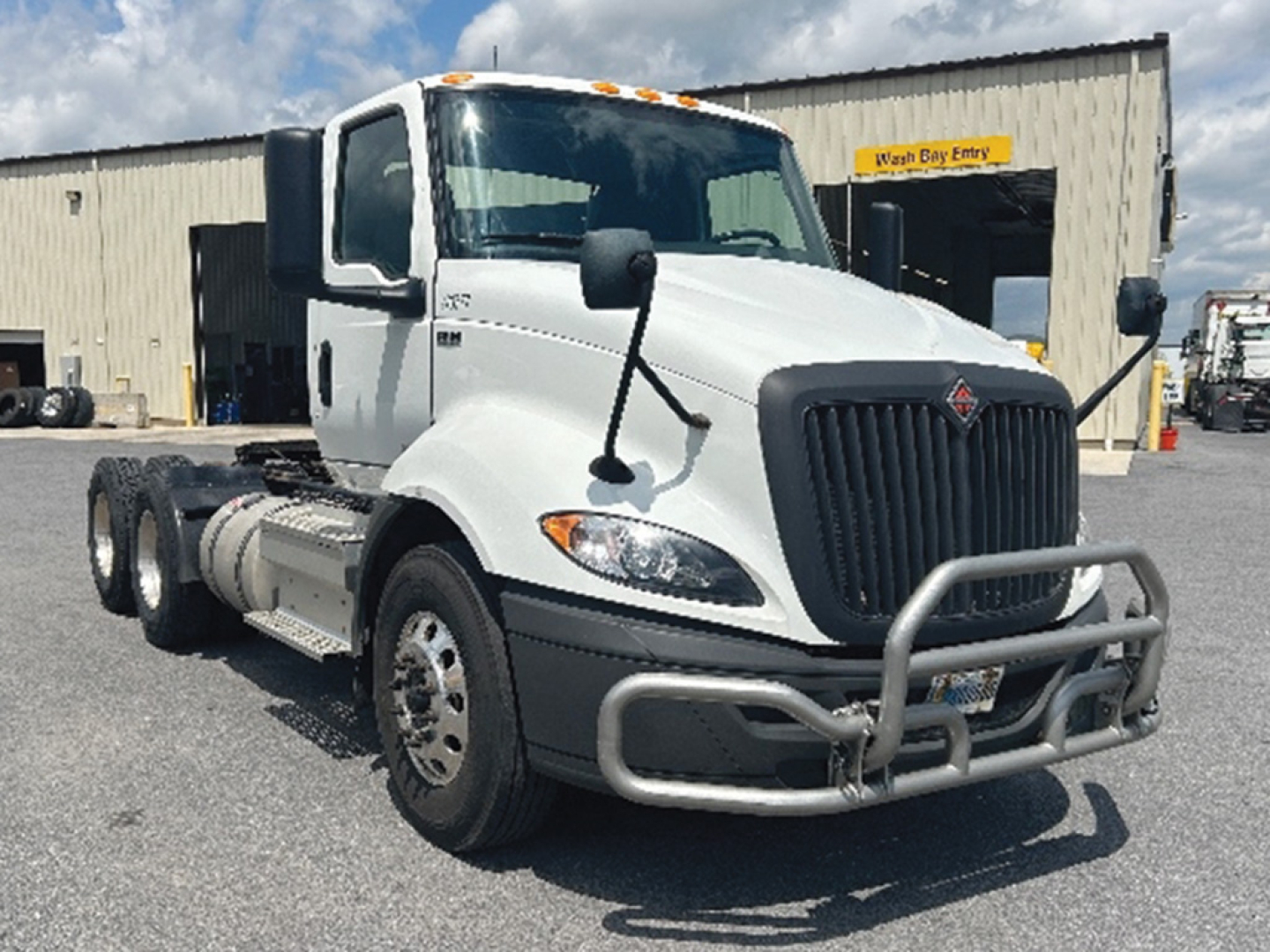 Truck cab showing front view of 2019 International RH613 with white body, black grille guard, chrome bumper, and dual rear axles.