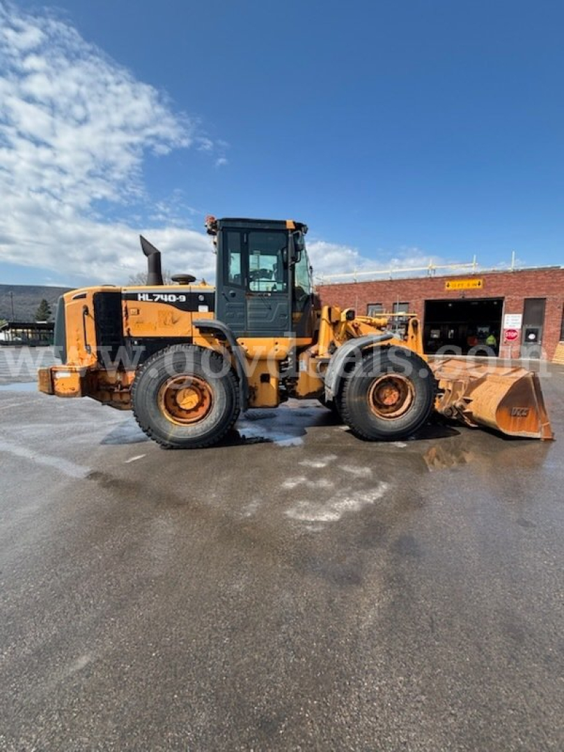 Hyundai HL740-9 wheel loader in profile with front bucket, side view showing tires and cab.
