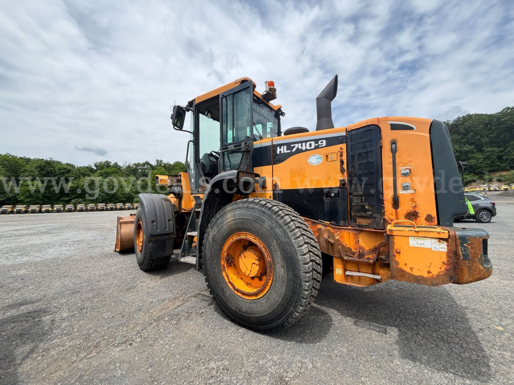 Hyundai HL740-9 wheel loader showing front and side with orange and black paint and HL740-9 decal on cab