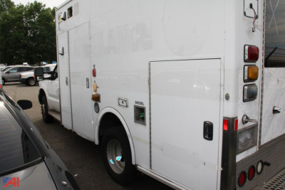 Ambulance rear quarter showing diesel fuel cap and latching door with rectangular panel; exterior white with taillights and hatch details.