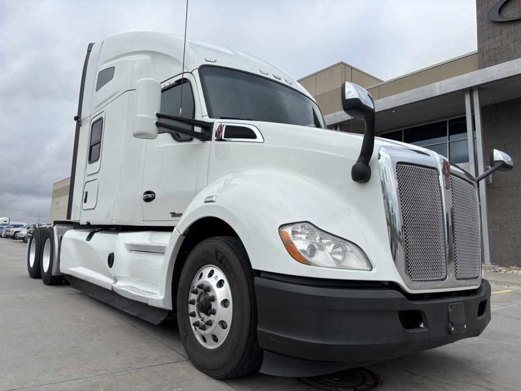 Kenworth T680 tractor unit in white, front-right view showing grille, bumper, and side mirror with sleeper cab.