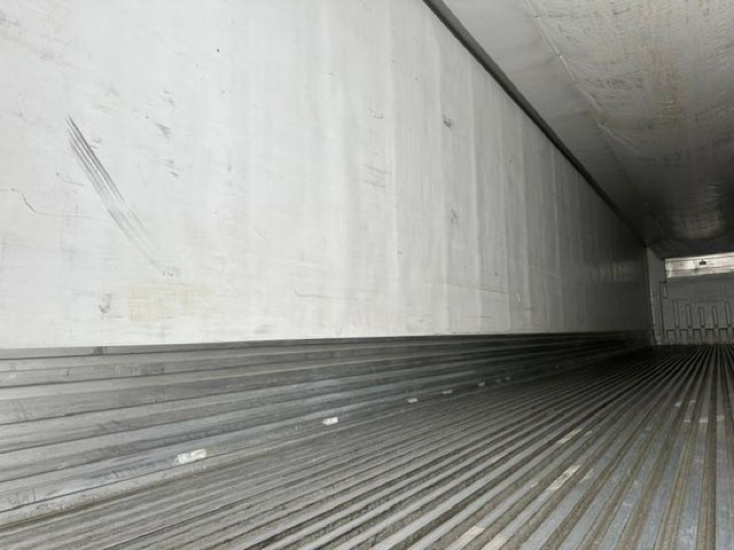 Trailer interior showing ribbed metal floor and side walls of a refrigerated trailer cargo area.
