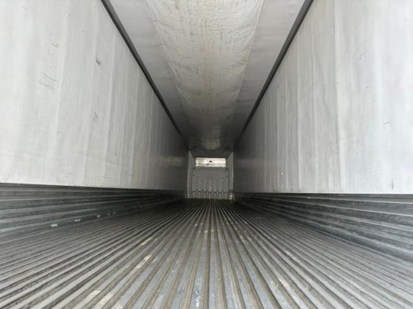 Trailer cargo area interior of a 2016 refrigerated utility trailer, long rectangular box with ribbed floor and metal walls, perspective from rear opening