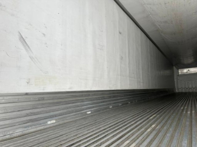 Trailer interior showing ribbed metal floor and side walls of a refrigerated trailer cargo area.