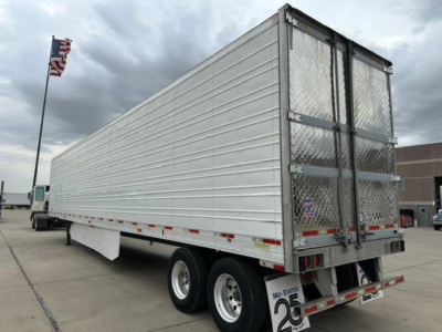 Trailer side view of a 2016 utility reefer with metal siding and rear doors, dual rear axles, and diamond plate gate.