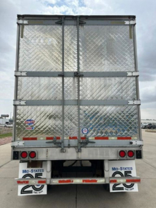 Trailer rear view showing metal diamond-plate doors with hinges and latches, utility reefer trailer back, MID-STATES and DOT stickers visible.