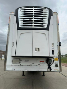 Rear view of a 2016 refrigerated trailer with a vertical cooling unit and raised landing gear, stock U90977, VIN 1UYVS253XGU494807.