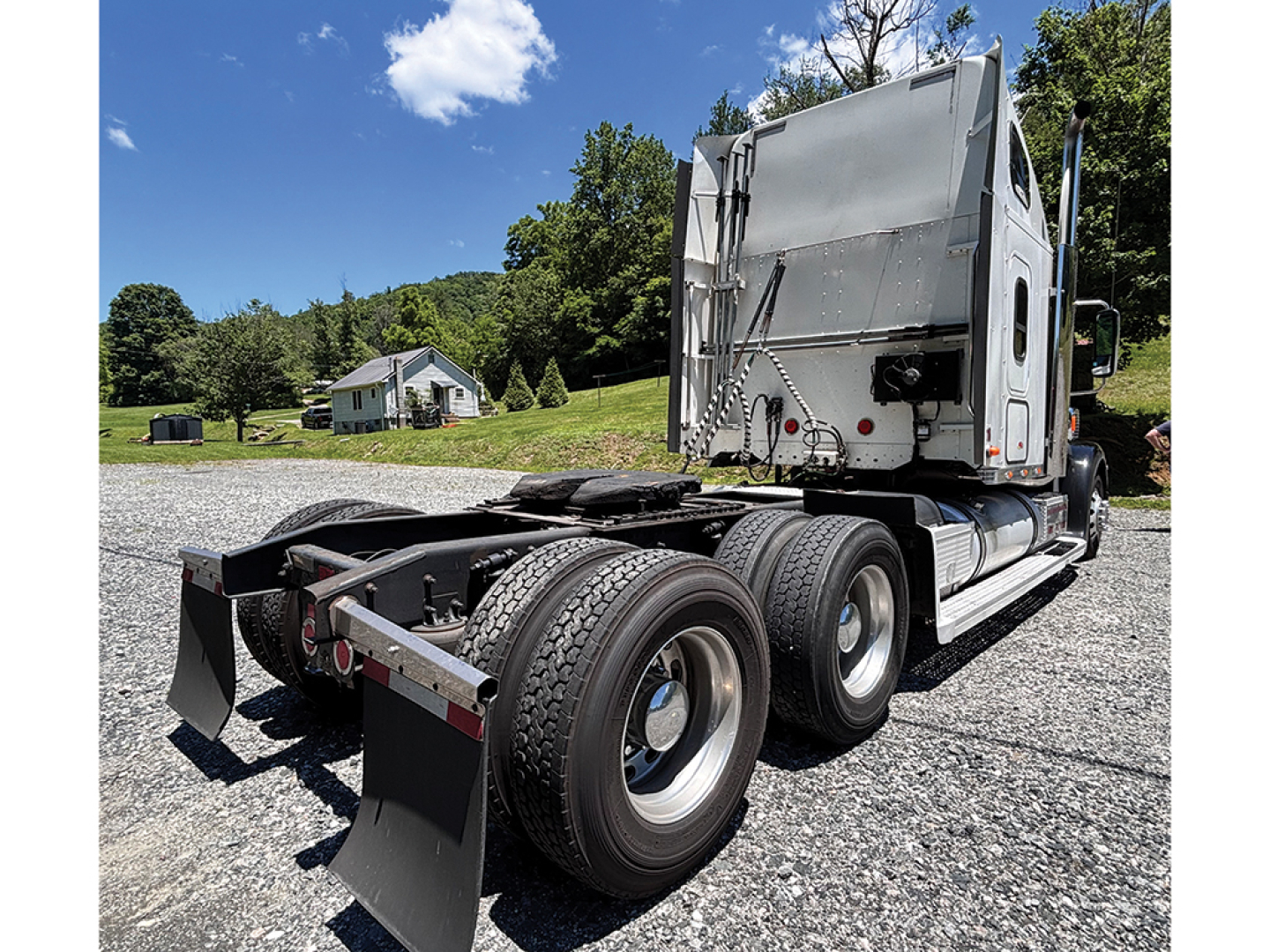 Freightliner Coronado truck chassis and rear sleeper cab view showing dual rear axles and mud flaps.
