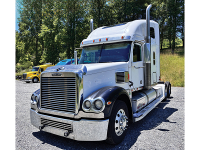 Freightliner Coronado truck shown in daylight with chrome grille, large bumper, dual exhaust stacks, and sleeper cab.