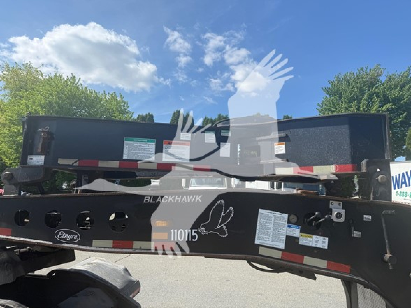 Trailer hitch showing BlackHawk 110105 beam with warning labels and stickers on a lowboy trailer frame.
