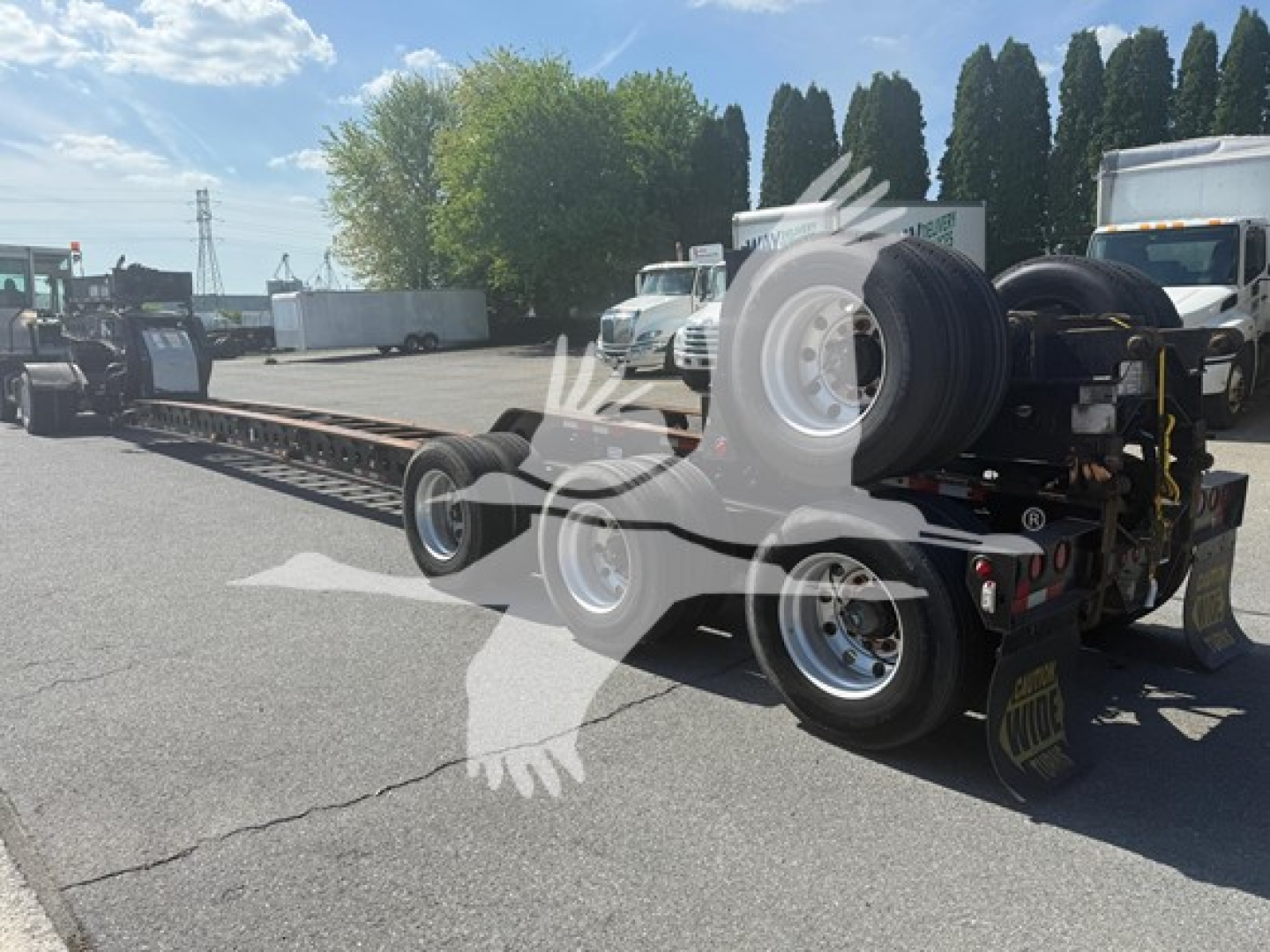 Lowboy trailer with a beam trailer and rear wheels visible.