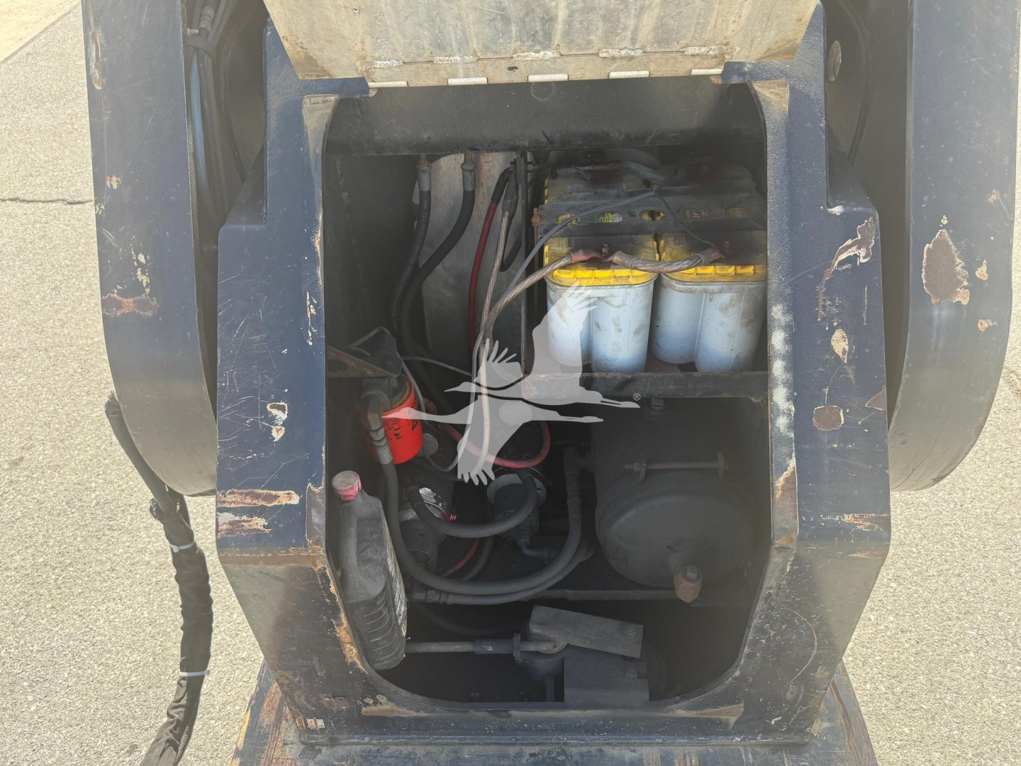 Engine bay of 2014 Etnyre Beam trailer showing hydraulic reservoir and battery area with hoses and wiring.